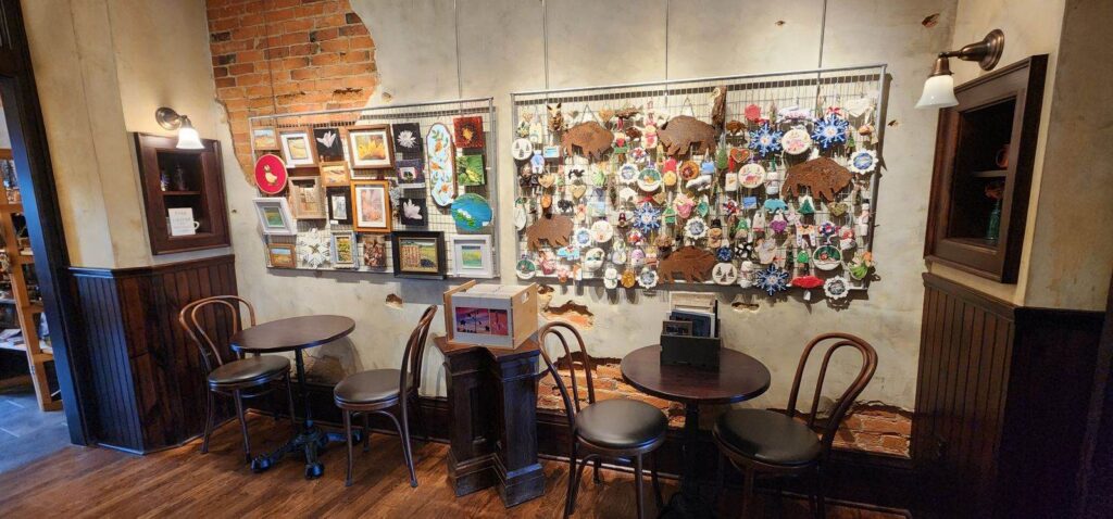 Display of hanging wall art with tables and chairs in front.